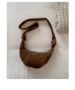 Détail du sac croissant en daim marron foncé avec empiècements et bandoulière nouée