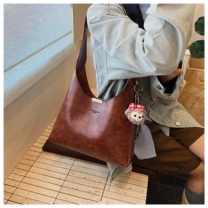 Detail of vintage brown textured PU leather hobo bag with top metal trim and plush charm