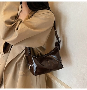 Deep brown oil wax leather shoulder bag detail with silver buckle on trench coat