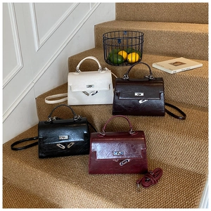 Group display of four glossy leather handbags with metal twist locks on stairs