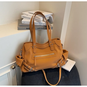 Detail of a ginger yellow faux leather tote bag with multiple pockets and matte finish