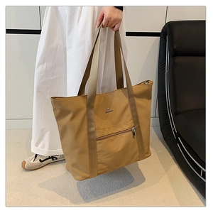 Détail du sac fourre-tout en nylon kaki avec poche zippée et logo métallique chic