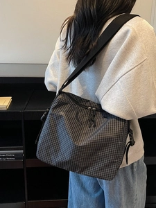 Large plaid canvas tote bag with adjustable strap worn as crossbody shoulder bag
