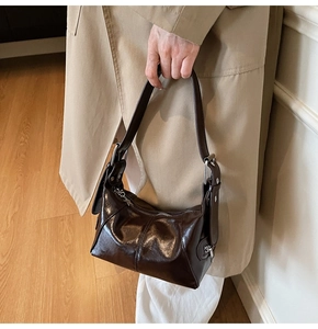 Detail of glossy dark brown leather shoulder bag with silver hardware and zipper