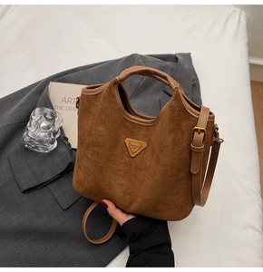 Gros plan du sac seau en daim marron avec bandoulière en cuir sur un blazer gris