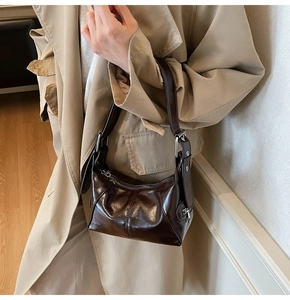 Polished dark coffee brown shoulder bag styled with a beige trench coat on a model