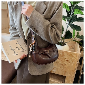 Detail of vintage brown leather hobo bag with knotted belt strap and beaded charm pendant
