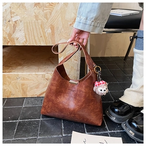 Detailed close-up of brown vintage bucket bag with metal buckle and plush charm