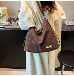 Detail of vintage brown hobo bag with exposed stitching and metallic logo tag