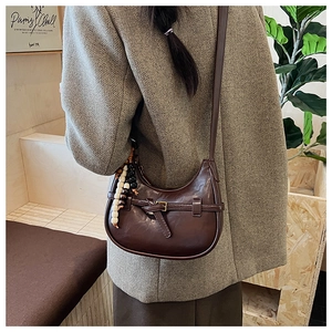 Detail of dark brown semi-circle crossbody bag with vintage buckle and bead charm
