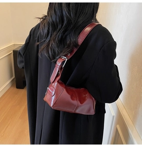 Detail of glossy burgundy faux leather underarm bag with silver zipper decoration