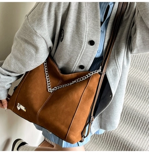 Detail showing vintage caramel suede tote bag with thick silver metal chain and strap