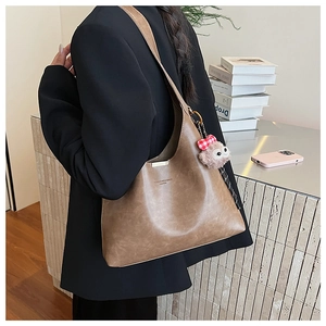 Brown textured hobo bag with gold hardware and plush lamb charm shown on a model