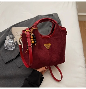 Vue détaillée du sac seau bordeaux mat avec logo doré et pendentif en perles de bois