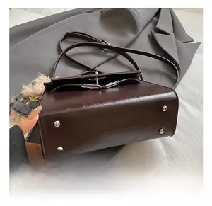 Detail view of the brown leather bag bottom featuring four silver metal protective studs