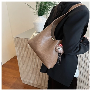 Detail of brown PU leather hobo bag with a cute plush doll charm and letter embossing