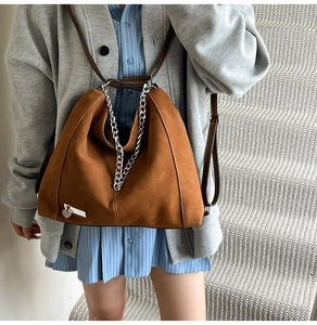 Detail view of brown faux suede hobo bag featuring silver chain and heart charm