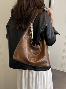 Sac hobo vintage en cuir marron avec pendentif perlé porté par un mannequin en ville