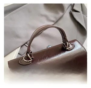 Detail of reinforced round handle and silver twist lock on dark brown leather bag
