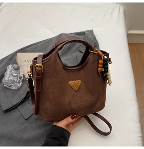 Détail du sac seau en daim marron avec breloque en perles de bois et bandoulière