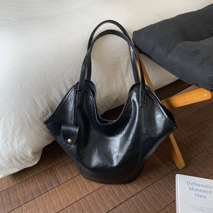 Close-up of black PU leather tote bag showing oil-wax texture and golden metal charm