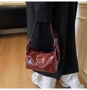 Close-up of burgundy glossy leather shoulder bag with star zipper and side brand logo detail
