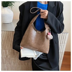 Detailed side view of brown matte PU leather hobo bag with pink plush lamb pendant accessory
