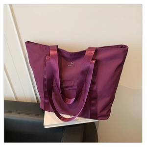 Détail du cabas en nylon violet avec larges bretelles, poche zippée et logo en métal