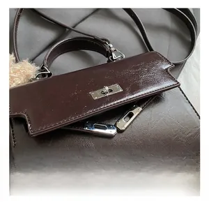 Detailed macro view of dark brown oil wax leather texture and silver buckle on the handbag