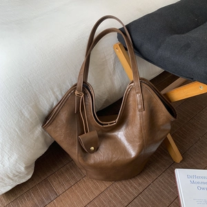 Detail of a brown leather tote bag with natural texture and matching mini pouch accessory
