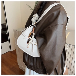 Detailed close-up of a white leather crescent bag featuring decorative wooden beads