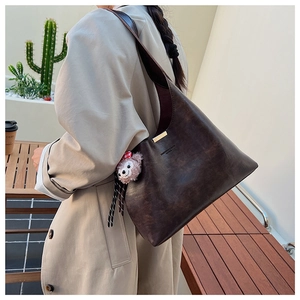 Detail of deep brown retro leather bucket bag with gold metal hardware and bear charm