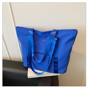 Détail du sac cabas bleu roi en tissu Oxford avec larges anses et logo métallique