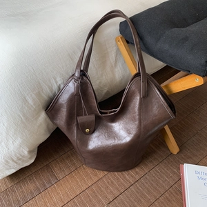 Detail of a dark brown vintage tote bag with gold snap buckle on high-quality leather
