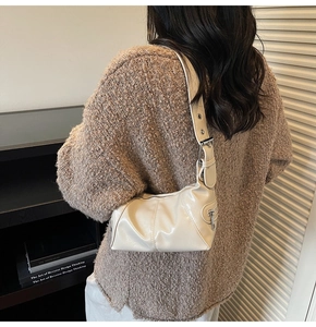 Close-up of cream white glossy shoulder bag showing smooth faux leather texture and detail