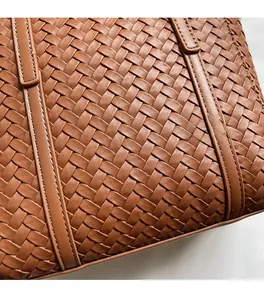 Close-up of tan leather woven pattern and stitching on a handheld bucket bag