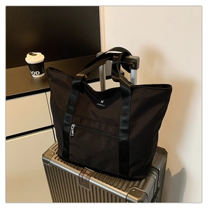 Sac fourre-tout noir sur valise argentée, idéal voyage avec poche frontale zippée
