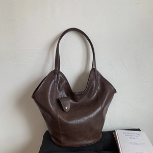 Detail of a dark brown vintage tote bag with gold button accents in a cozy setting