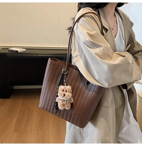 Detail of woven leather texture on a large brown tote bag with a cute bear charm