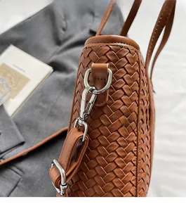 Detailed close-up of brown woven bucket bag featuring silver hardware and adjustable strap