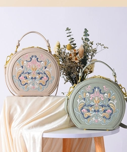 Detail of elegant floral embroidery on semi-circle leather bags with golden zippers