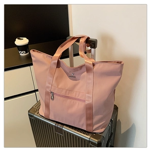 Sac fourre-tout en tissu Oxford rose posé sur la poignée d'une valise