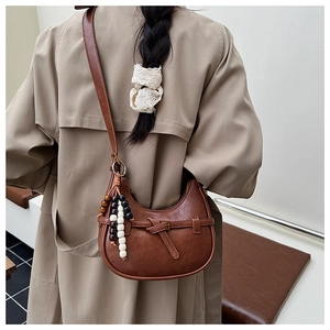 Detail of retro brown hobo bag with ethnic style wooden beads on a stylish trench coat