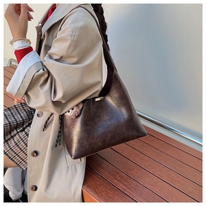 Detail of vintage brown leather shoulder bag styled with an autumn khaki trench coat outfit