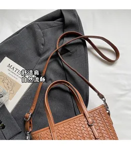 Detailed view of brown woven leather tote bag texture on a grey suit jacket