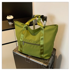 Gros plan d'un grand sac fourre-tout vert en nylon sur une valise avec poche zippée