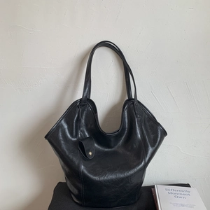 Close-up of black leather tote bag with fine grain texture and stylish side mini pouch