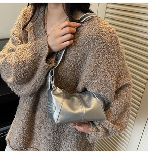 Detail of silver metallic Y2K shoulder bag with decorative zipper and textured finish