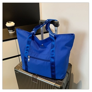 Sac fourre-tout bleu en nylon sur valise montrant le tissu imperméable et logo