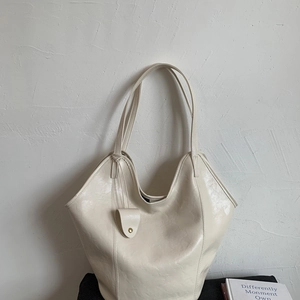 Detail of beige tote bag with smooth faux leather texture and gold buckle charm